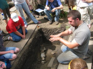 A Western Michigan University student discusses a building foundation at Fort St. Joseph with middle school students in the archaeology camp (Photo: Jessica Hughes. Courtesy of the Fort St. Joseph Archaeological Project)